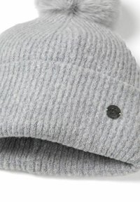 Svetlo šedá pletená zimná čiapka s ohnutým okrajom, huňatý pom-pom navrchu a malým okrúhlym kovovým logom na okraji.