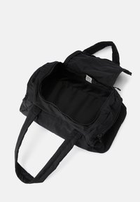 Czarna torba sportowa z teksturowanym materiałem zewnętrznym, z zapięciem na zamek błyskawiczny na górze i dwoma długimi uchwytami. Wnętrze wykończone gładkim, niepodświetlanym materiałem.