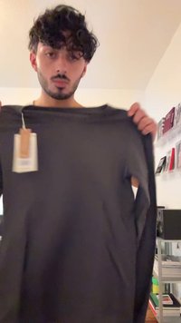 Zwarte langemouwen shirt van zachte stof, met een ronde halslijn en een label aan de linkermouw. Eenvoudig, onopgesmukt ontwerp.