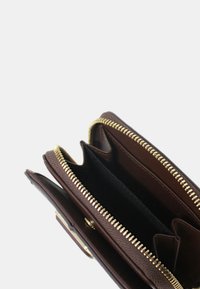 Portafoglio in pelle marrone con chiusura a cerniera, dotato di più scomparti e esterno dalla texture lavorata. Dettagli in metallo color oro.