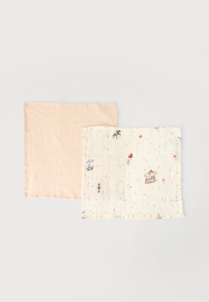 Two soft muslin cloths, one plain pale peach and one off-white with small colorful carnival-themed illustrations.