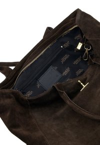 Brown suede tote bag with a zippered closure. Interior features black fabric lined with repeated logo pattern and an inside pocket. Gold hardware accents.