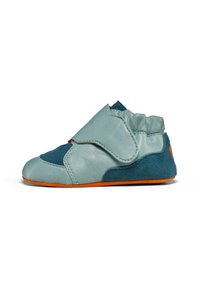 Zapato de cuero en azul claro y azul oscuro con una suela naranja. Presenta una forma curva, textura suave y una tira de Velcro para el cierre.