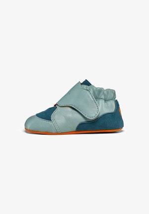 Chaussure en cuir bleu clair et bleu foncé avec une semelle orange. Présente une forme courbée, une texture douce et une sangle Velcro pour la fermeture.