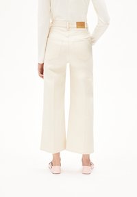 Wijduitlopende crèmekleurige denim jeans met een hoge taille, voorzien van dubbele achterzakken en een tan lederen logo op de tailleband.