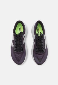 Purple athletic shoes with a mesh upper, black laces, silver accents, and a cushioned white sole. Bright green insole marked "FUELCELL."