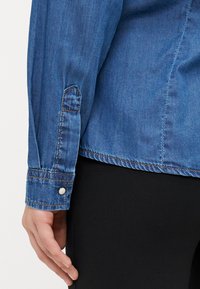 Τζιν πουκάμισο με μακριά μανίκια, διαθέτει κουμπωτό μανίκι και αντίθετη ραφή. Πλούσιο μπλε χρώμα και μαλακή υφή.