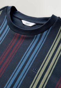 Granatowy T-shirt z krótkim rękawem w pionowe paski w odcieniach niebieskiego, czerwonego i zielonego. Posiada okrągły dekolt oraz subtelną haftowaną logo na klatce piersiowej.
