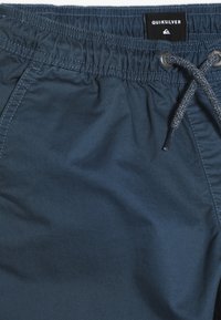 Bañador de color navy hecho de tejido suave, con cinturilla elástica, cierre con cordón y detalles de costura sutiles.