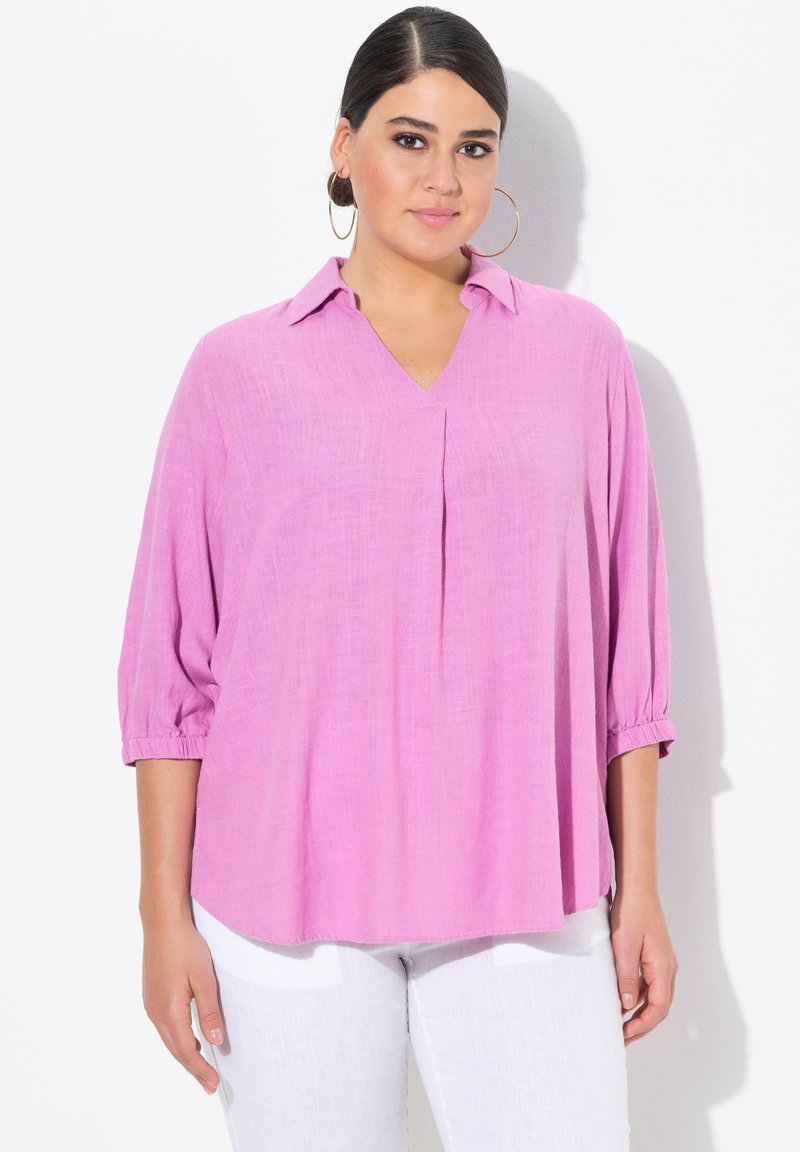 Blusa leggera e tessuta, di colore rosa, con scollatura a V e maniche a tre quarti, caratterizzata da una sottile trama e una vestibilità rilassata.