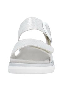 White sandals with perforated upper, two strap design, a silver buckle accent, and a cushioned sole. Flat, lightweight, and open-toe style.