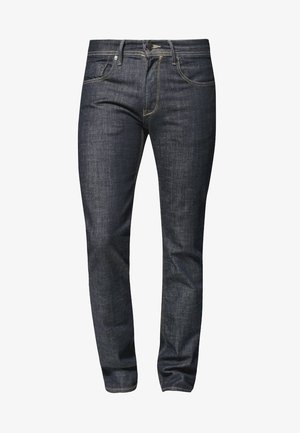 Vaqueros de mezclilla ajustados en azul oscuro con cinco bolsillos, cierre de botón y costuras visibles sobre un fondo blanco.