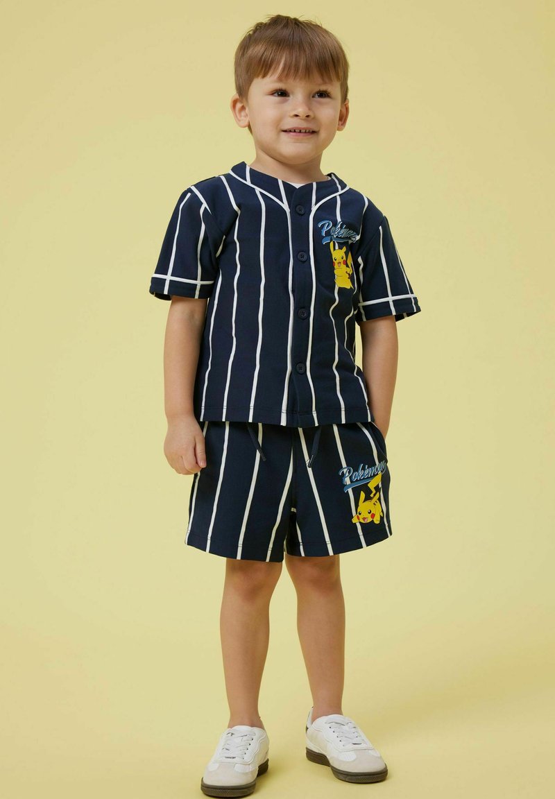 Completo corto a righe navy con camicia a bottoni che presenta una grafica di Pikachu. I pantaloni shorts hanno una vita elastica e un dettaglio coordinato di Pikachu.