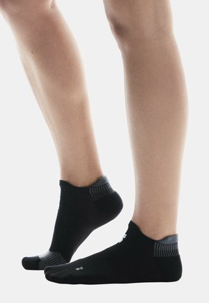 Chaussettes noires jusqu'à la cheville avec des accents côtelés gris, présentant un design ajusté et un tissu texturé. Les chaussettes couvrent la cheville mais pas la jambe.