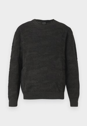 Mustan neuleen, jossa on tekstuurinen siksak-kuvio, pyöreä kaula-aukko ja pitkät hihat. Kangas on pehmeää ja hengittävää.