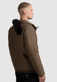 Brown insulated jacket with a black faux fur hood. Smooth texture, zip front, and side pockets. Minimalistic design, well-fitted silhouette.