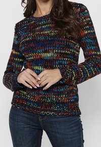 Kleurrijke gebreide trui met horizontale strepen in rood, blauw, groen en geel, met een ronde hals en lange mouwen.