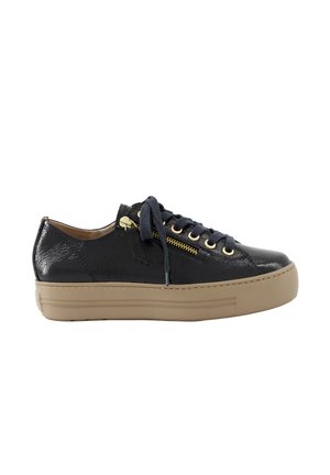 Black low-top sneaker with thick beige sole, black laces, gold zipper, and eyelets, side view on white background.