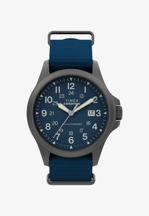 Timex Expedition watch with a dark gray case, blue dial, luminous numbers, and a textured blue fabric strap. Features date window at 3 o'clock.