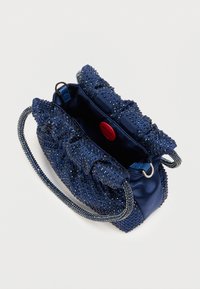 Námornícky modrá kabelka s volánovým dizajnom, pokrytá kryštálikmi. Vyznačuje sa textúrovaným povrchom, saténovým materiálom a kovovým reťazovým remienkom.