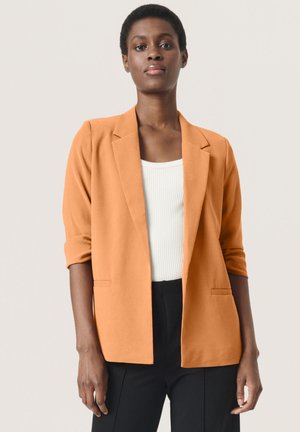 Oranžový blazer vyrobený z texturované tkaniny, s jediným knoflíkem, klopovými límci a ohrnutými rukávy. Nositelný přes bílé tričko.