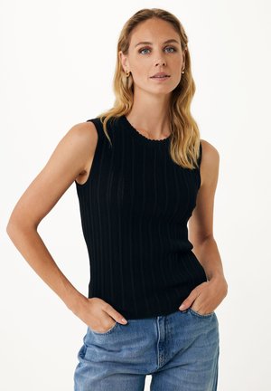 Top senza maniche nero a coste con scollatura ondulata, realizzato in un materiale a maglia texturizzato. Abbinato a jeans in denim blu chiaro.