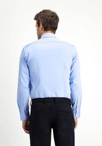 Lichtblauw overhemd met lange mouwen, een gestructureerde kraag en manchetknopen, gecombineerd met zwarte broek; heeft een gladde textuur en een op maat gemaakte pasvorm.