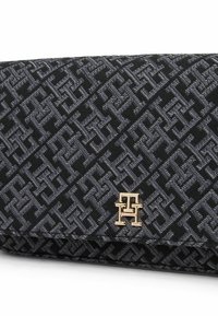Pochette in tessuto nero teksturizzato con un motivo geometrico. Accentatura del logo in tono oro sulla parte anteriore. Chiusura a scatto con silhouette piatta.