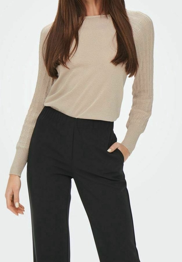 Beige gebreide longsleeve met geribbelde textuur en aansluitende mouwen, gecombineerd met zwarte wijde broek met zijzakken.