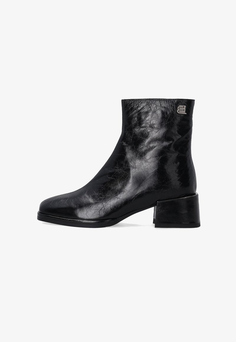 Schwarze Knöchelstiefel mit glänzender Oberfläche, quadratischer Spitze, niedrigem Blockabsatz und geprägtem Logodetail an der Seite. Glattes Ledertexture.