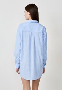 Camicia a maniche lunghe azzurro chiaro con motivo testurizzato, colletto button-down, yoke posteriore singolo e dettagli ai polsini con bottone.