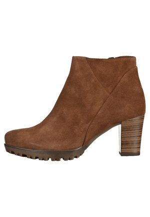 Brun ruskind-ankelstøvle med rundet tå, træblokhæl og struktureret sål. Har et udskåret design i siden for ekstra detalje.