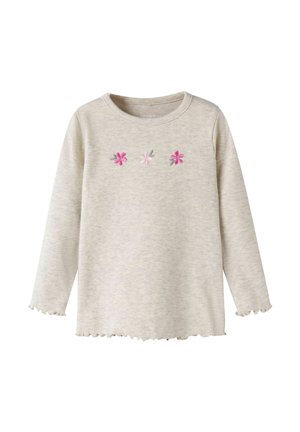 Jasnobeżowa, długorękawowa prążkowana koszulka z okrągłym dekoltem, marszczonymi mankietami i dołem, ozdobiona trzema małymi różowymi kwiatkami na wysokości klatki piersiowej.