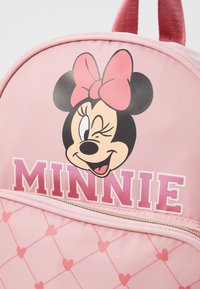 Ružový batoh s grafikou usmievajúcej sa kreslenej postavičky a s nápisom "MINNIE" v tučných ružových písmenách. Textúrovaný vzor obsahuje srdcia.