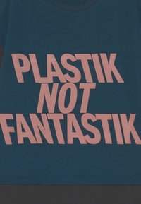 T-shirt azul escuro com grandes letras rosa claro a dizer "PLASTIK NOT FANTASTIK." Mangas curtas, gola redonda, material em algodão.