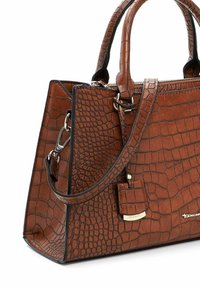 Brun faux læder taske med krokodilleprint, struktureret form, top håndtag og en aftagelig skulderrem; har et lille vedhæng.