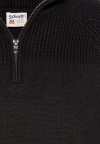 Czarny sweter dzianinowy z wysokim kołnierzem i ćwiartkowym zapięciem. Posiada prążkowaną teksturę, metalowy zamek błyskawiczny oraz metkę z logotypem blisko kołnierza.