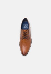 Chaussure habillée en cuir marron avec un motif texturé rappelant le crocodile, bout arrondi, lacets fins, et une doublure bleue avec logo.