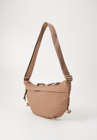 Bolso de hombro de nylon marrón con un diseño curvado, correa ajustable, cierre de cuerda y bolsillo con cremallera en la parte delantera. Acabado de tela texturizada.