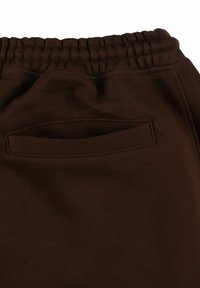 Brązowe dresy z elastycznym pasem, gładką fakturą oraz tylną kieszenią z przeszytym otwarciem.