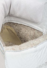 Witte leren schoen met een interieur van zacht beige vilt, gestikte naden en een gladde tan binnenzool. Minimalistisch ontwerp, geen zichtbare hardware.