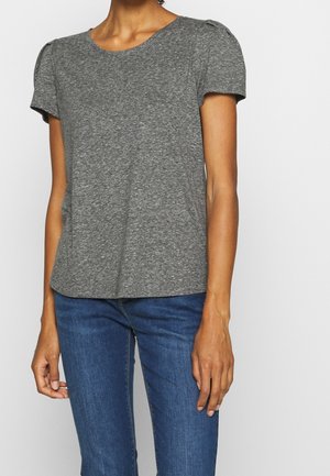 T-shirt gris à manches courtes en tissu doux et léger, avec un col rond et de subtils détails bouffants sur les épaules. Porté avec un jean bleu.