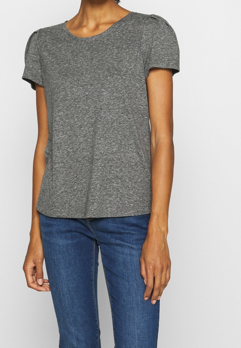 Grå T-shirt med korte ærmer i et blødt og let stof med rund hals og subtile puffdetaljer på skuldrene. Bæres med blå jeans.