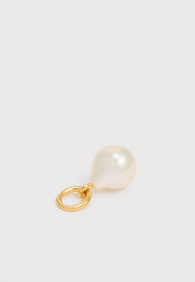Μονή ακανόνιστη λευκή πέρλα προσαρτημένη σε μικρό χρυσό κρίκο σε απλό ανοιχτό φόντο.