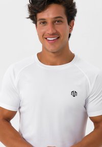 Hvid atletisk t-shirt med rund hals og korte ærmer. Har et lille sort logo på venstre bryst. Glat, letvægtsstof.