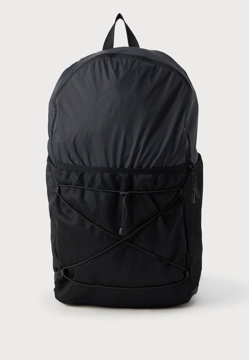 Zaino nero con un tessuto liscio e resistente. Presenta tasche laterali in rete, un design con cordino elastico sulla parte anteriore e una maniglia per il trasporto superiore.