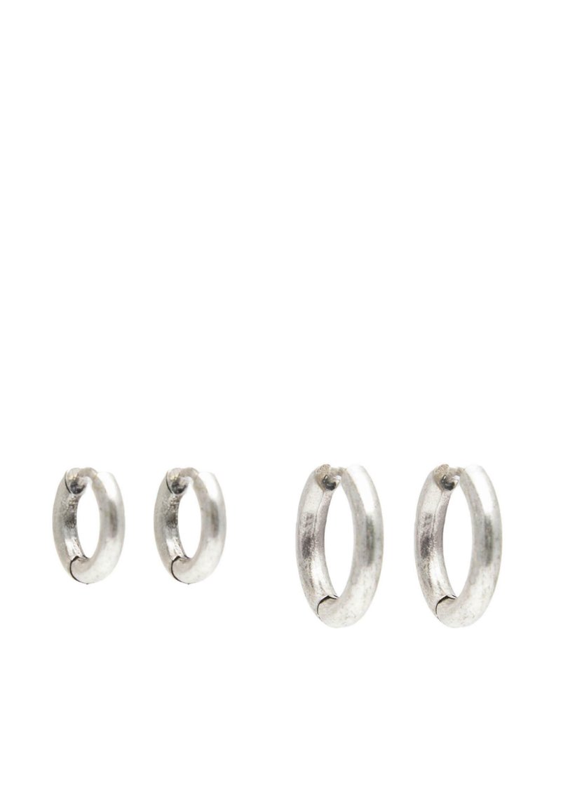 Två par enkla silver hoop-örhängen, ett mindre och ett större, visade på en vit bakgrund.