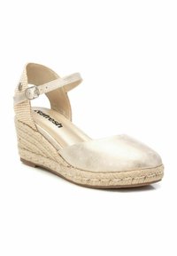 Espadrille de cuña con parte superior en un dorado metálico, una correa ajustable en el tobillo y una suela de yute trenzado con detalles texturizados.