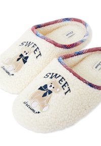 Zapatillas de felpa color crema con diseño bordado de oso de peluche, lazo azul oscuro y texto "DULCES sueños"; ribete a cuadros alrededor de la apertura.