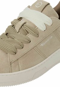Sneaker in suede beige con lacci crema a contrasto. Presenta una suola testurizzata e un branding minimale sul lato. Finitura liscia con dettagli cuciti.